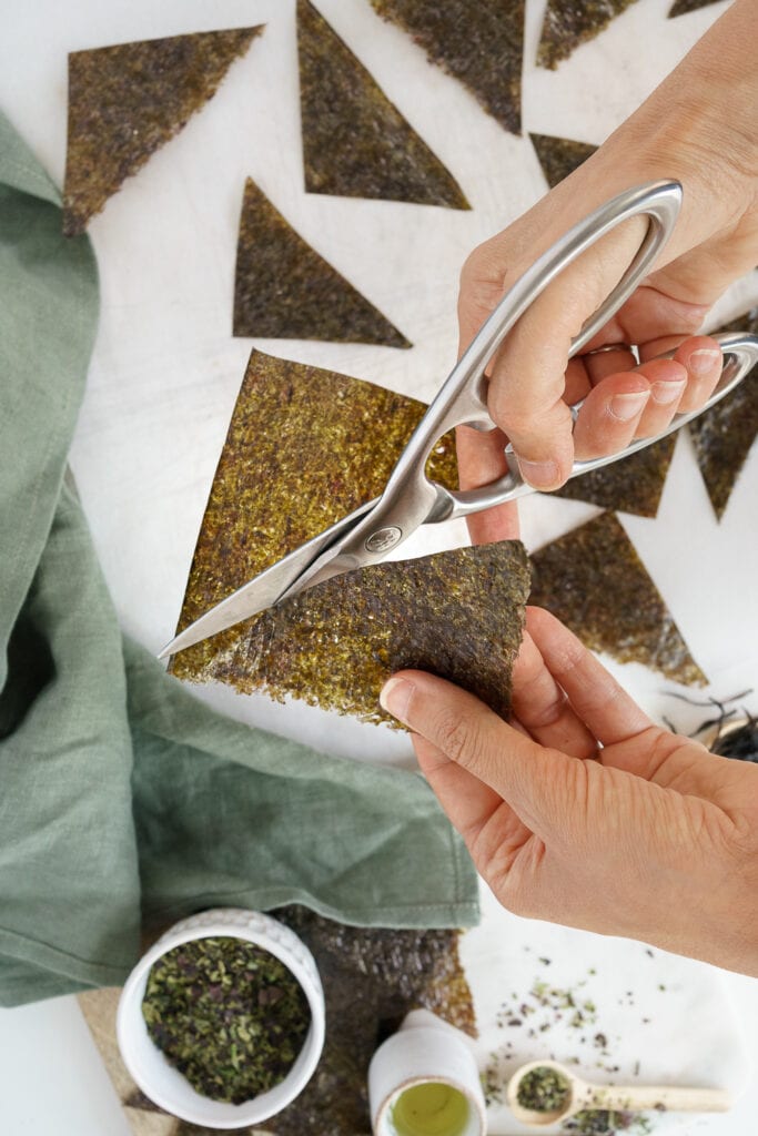 hands cutting seaweed sheets into triangles