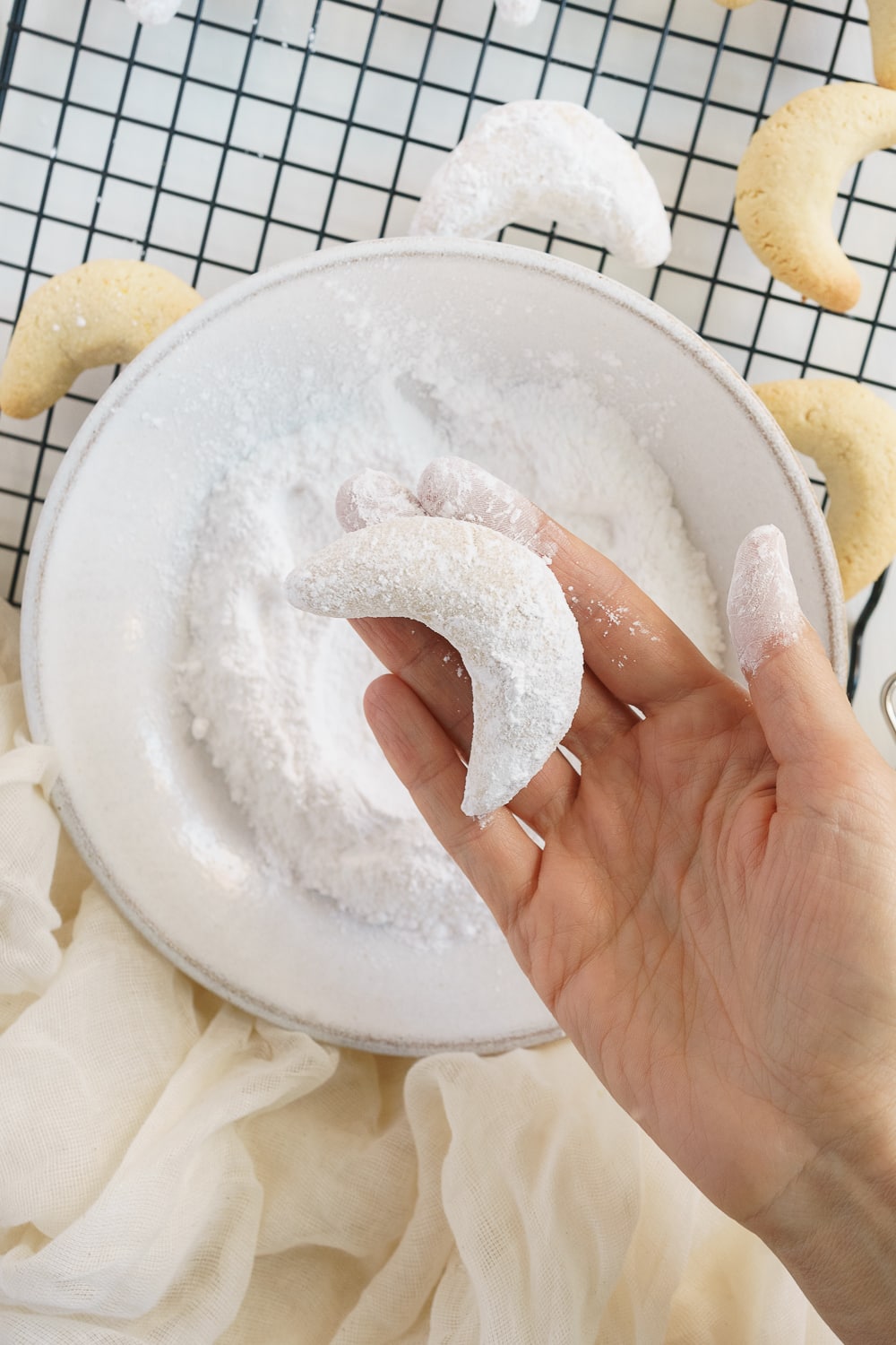 hand showing almond crescent cookie coated in powdered sugar