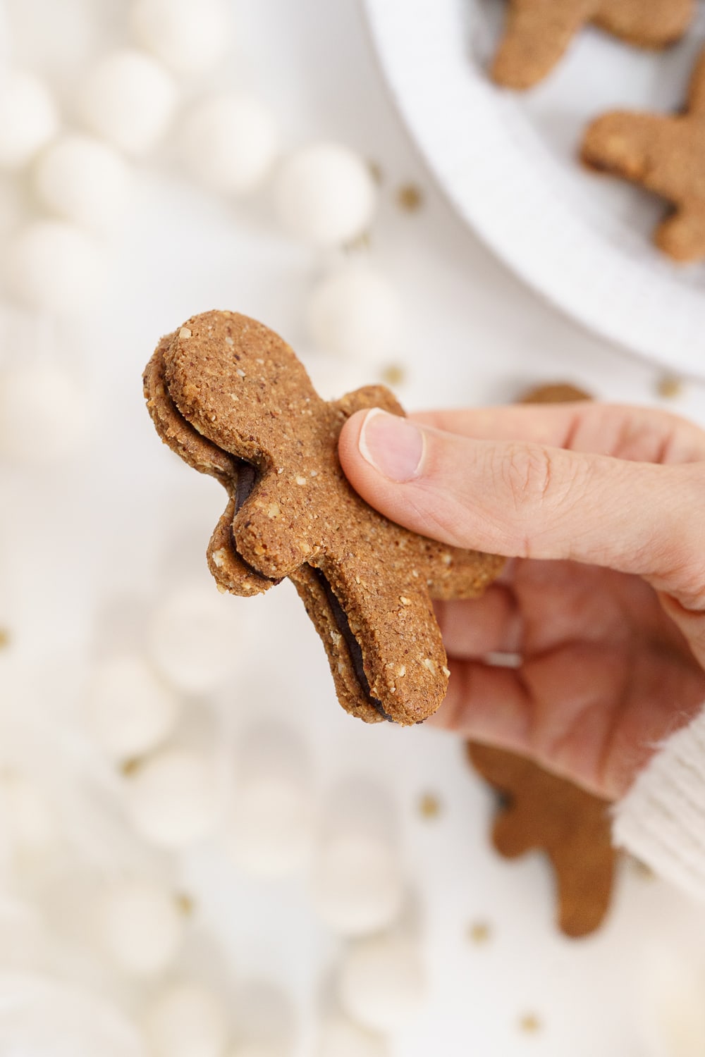 Hand holding gingerbread man sandwich cookie