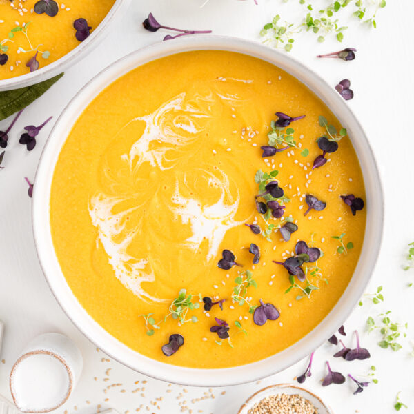 Carrot lentil ginger soup in a white bowl on the table.