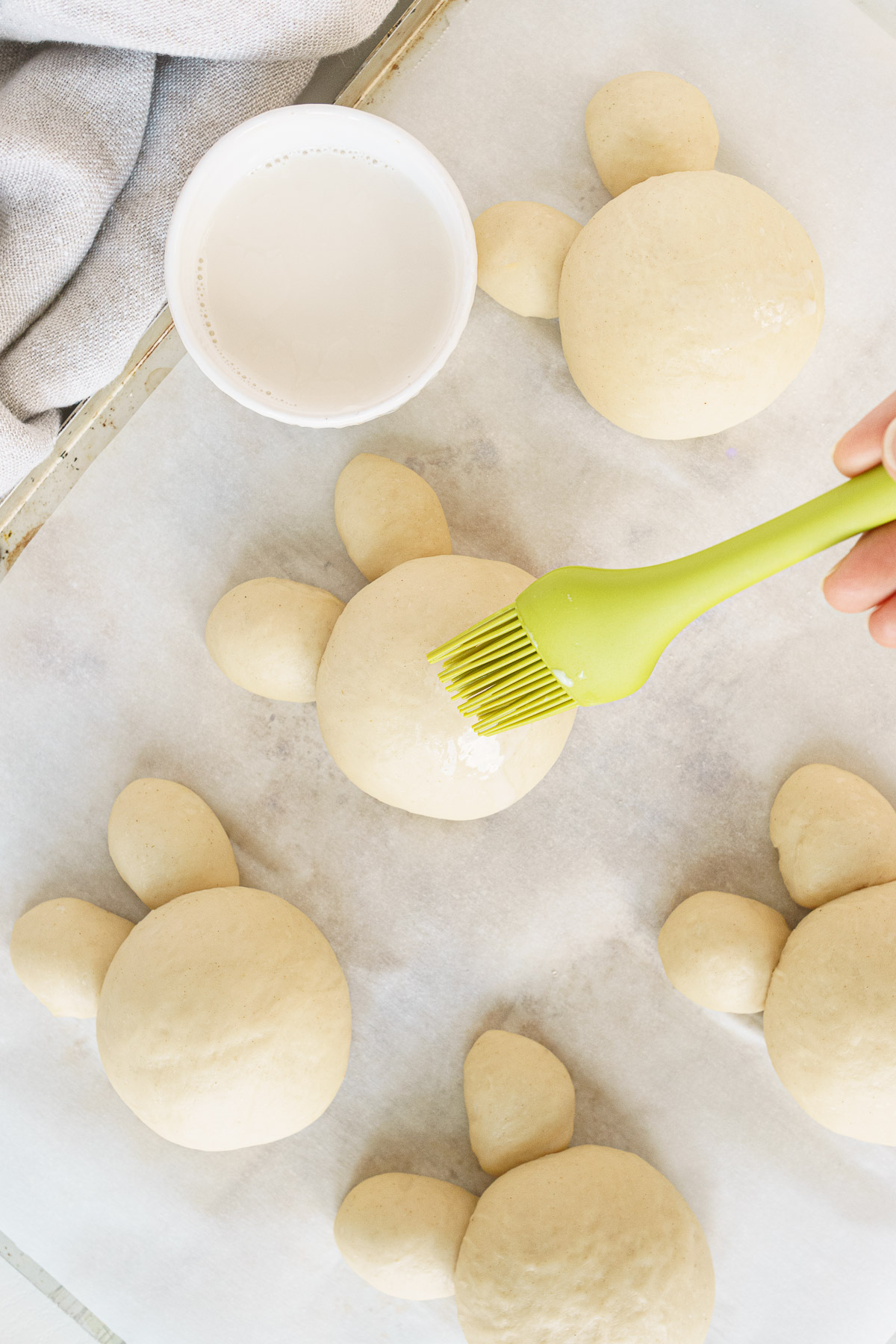 Brushing the brioche bunnies with milk.