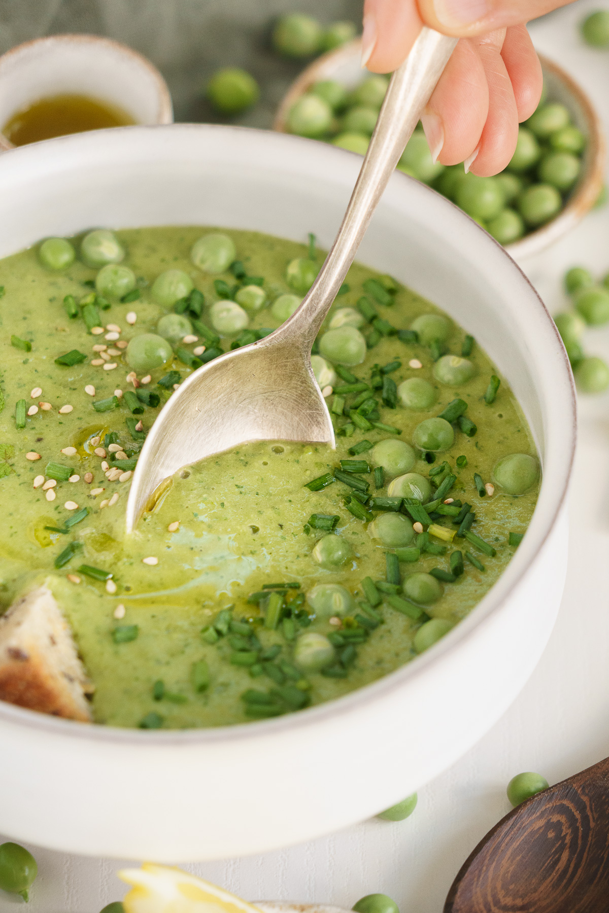 Spoon dipping into a bowl of fresh pea soup.