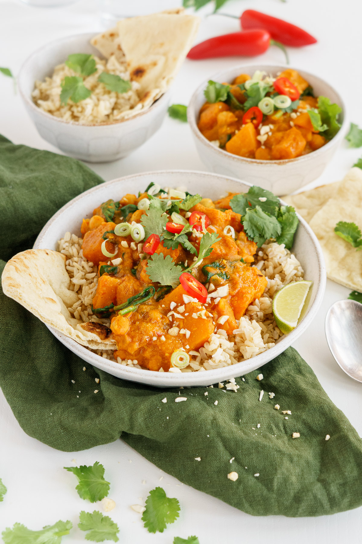Butternut squash curry served up on a table with limes, cilantro and pita.
