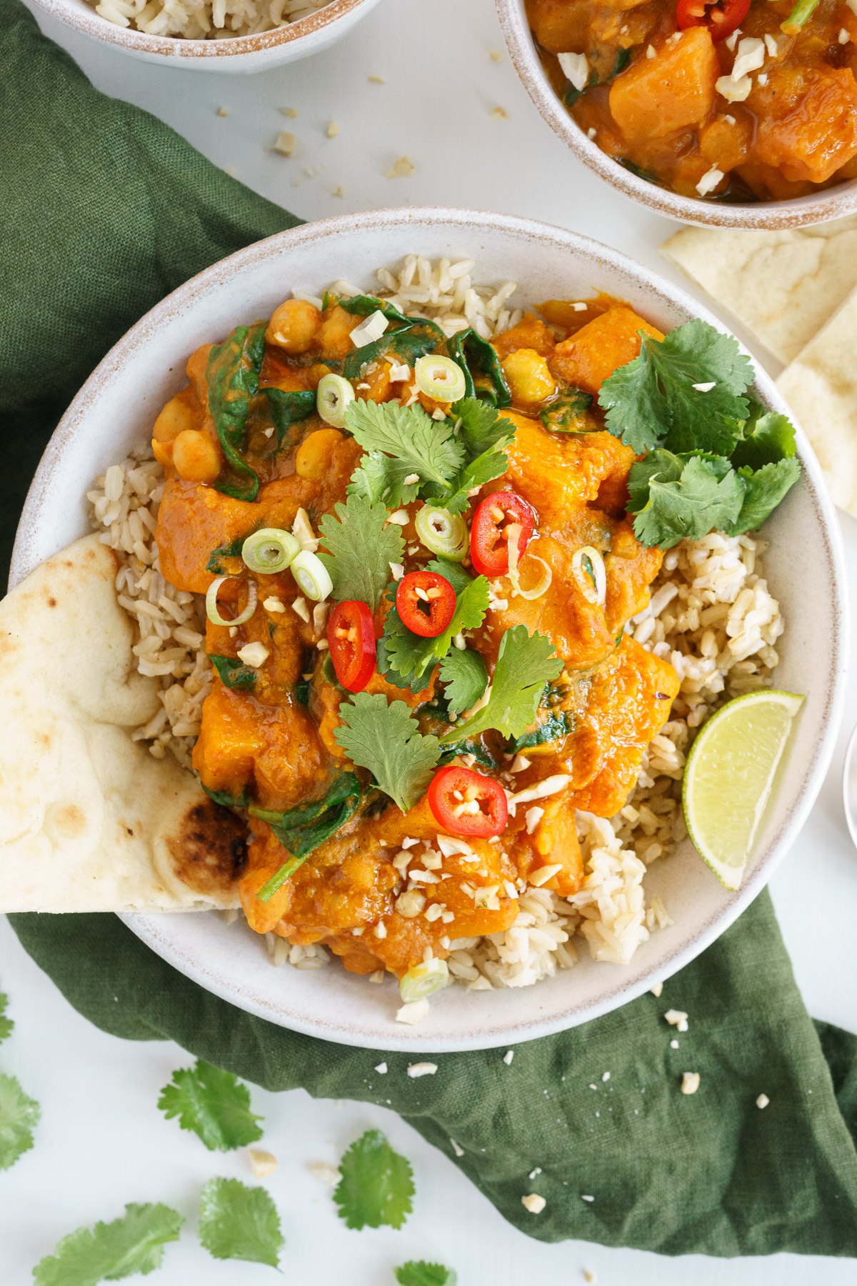 Bowl of butternut squash curry garnished with cilantro leaves and lime wedge.