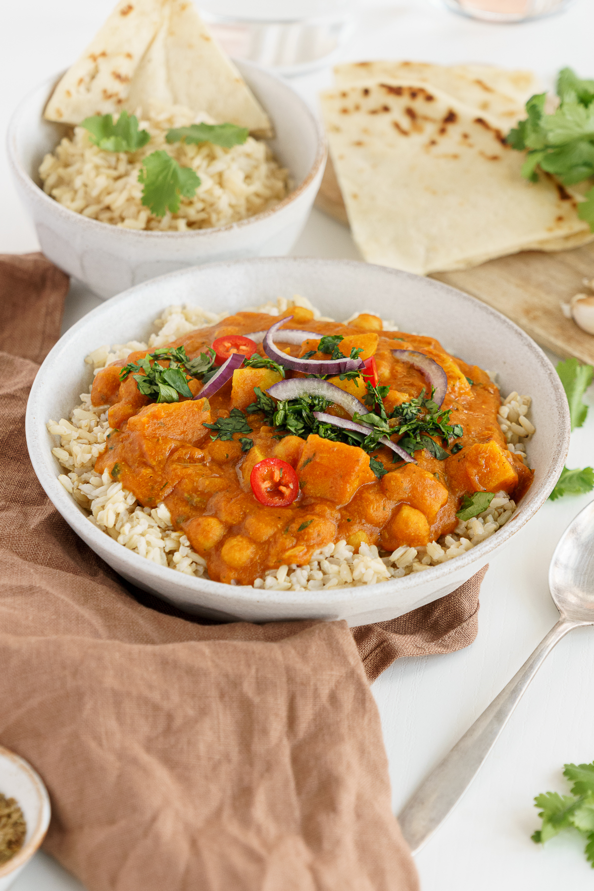 Chana aloo, chickpea potato curry in a bowl on the table with rice.