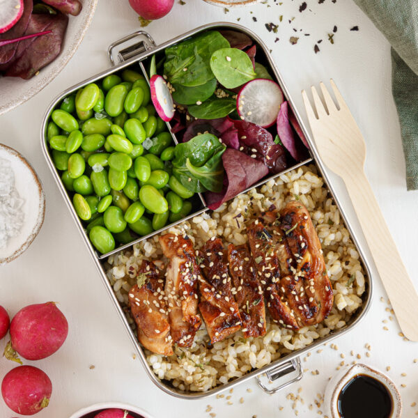 Chicken teriyaki bento box with easy to carry fork next to it and ingredients surrounding it.