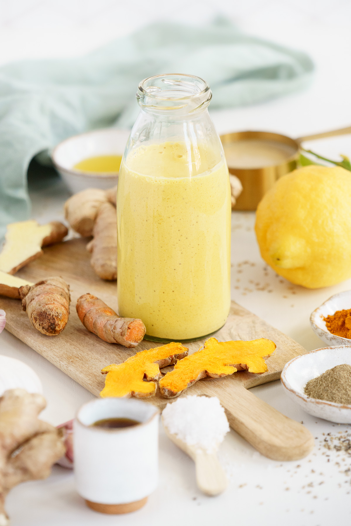 Jar of tahini dressing on the table with fresh turmeric and other ingredients.