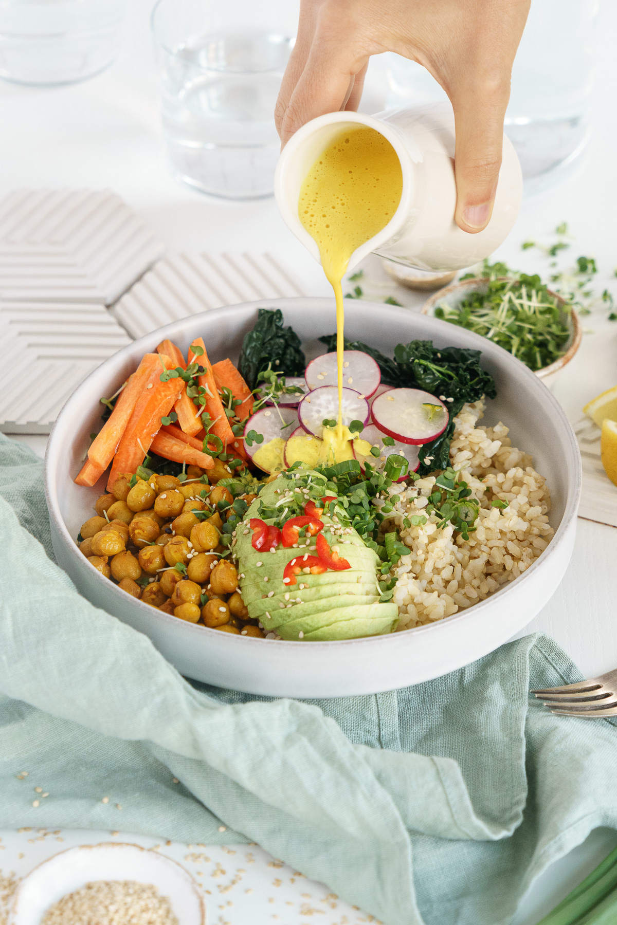 Salad with a jar pouring tahini dressing over the top.