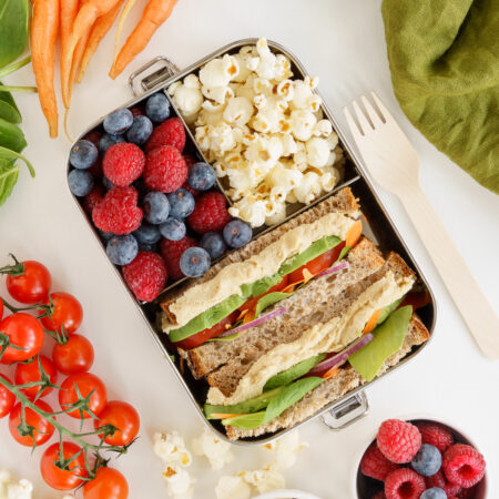 Vegan bento box with popcorn, berries and sandwich.
