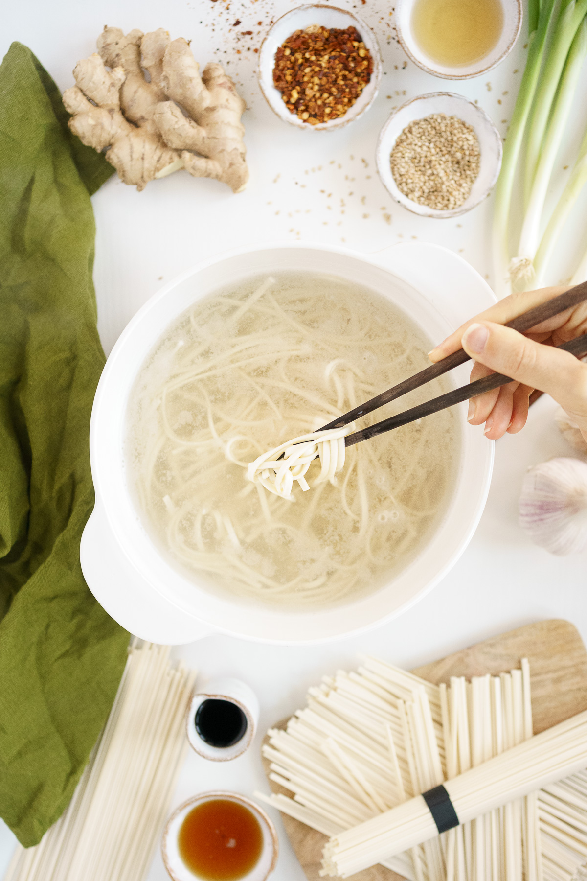 Chopsticks lifting noodles from pot.