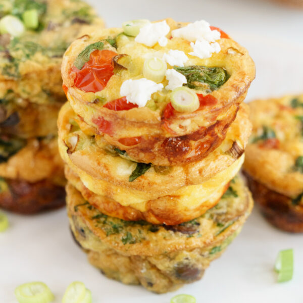 Three healthy egg muffins stacked with more behind them.
