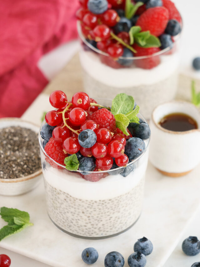 Two vanilla chia pudding cups on the table garnished with fresh berries.