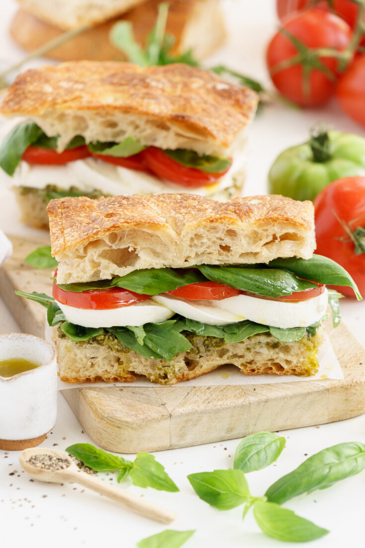 A caprese sandwich on a wooden cutting board on the table.
