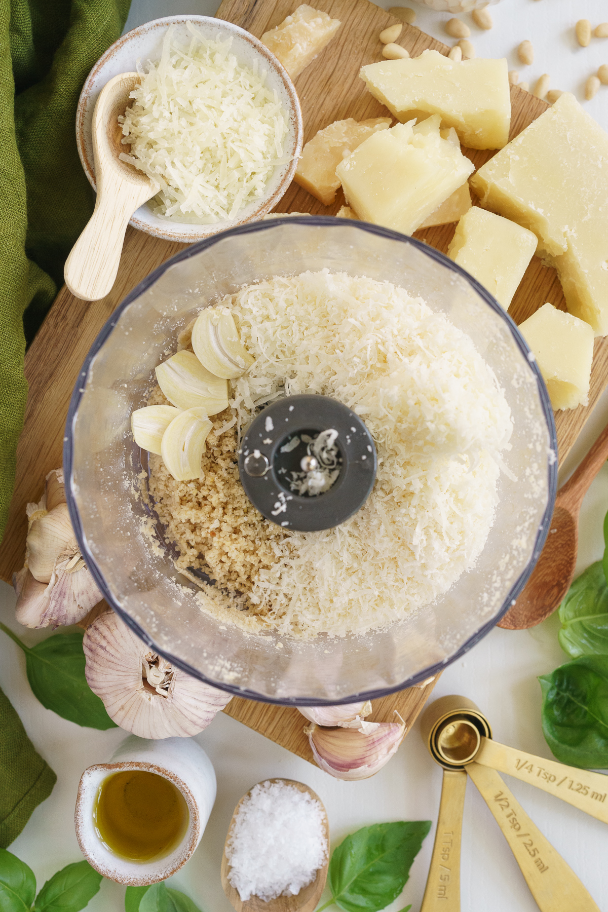 Adding garlic to the food processor to make basil pesto.