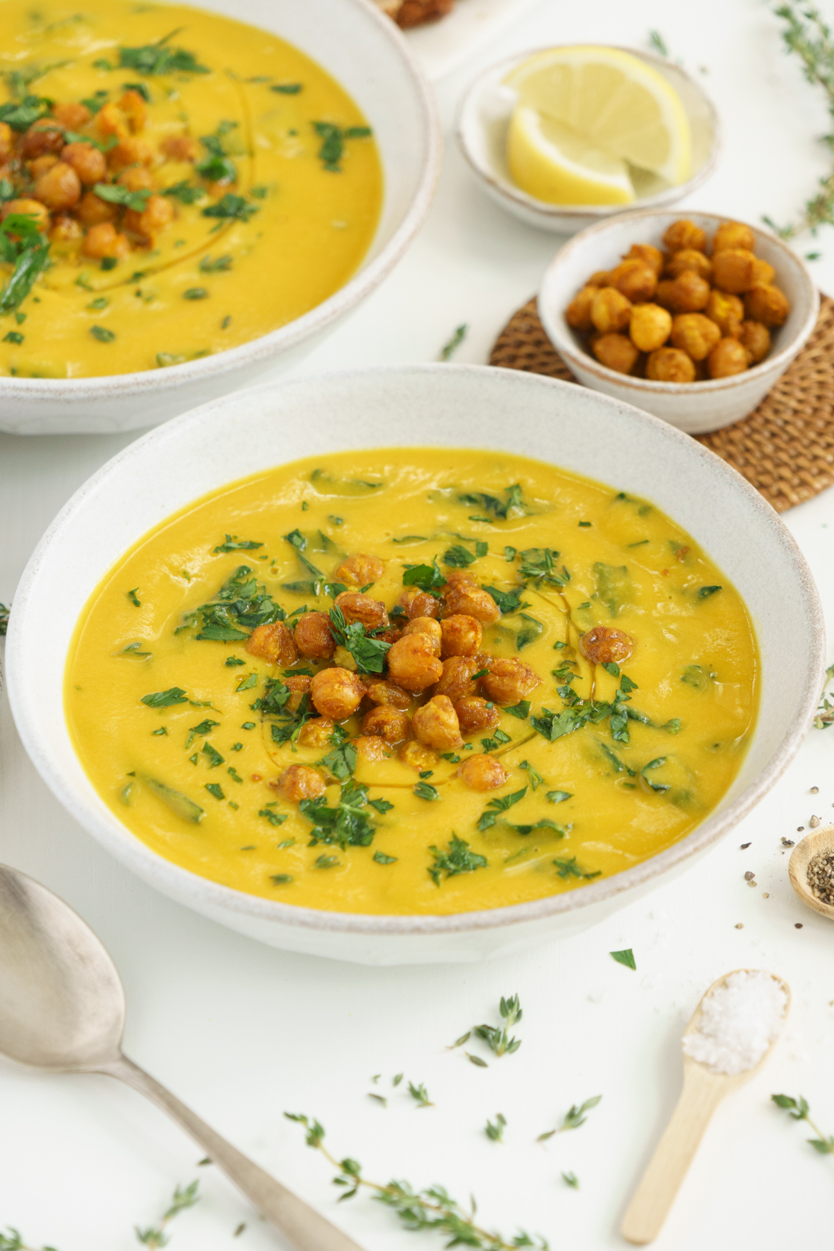 Two bowls of turmeric chickpea soup on the table with crispy chickpeas.