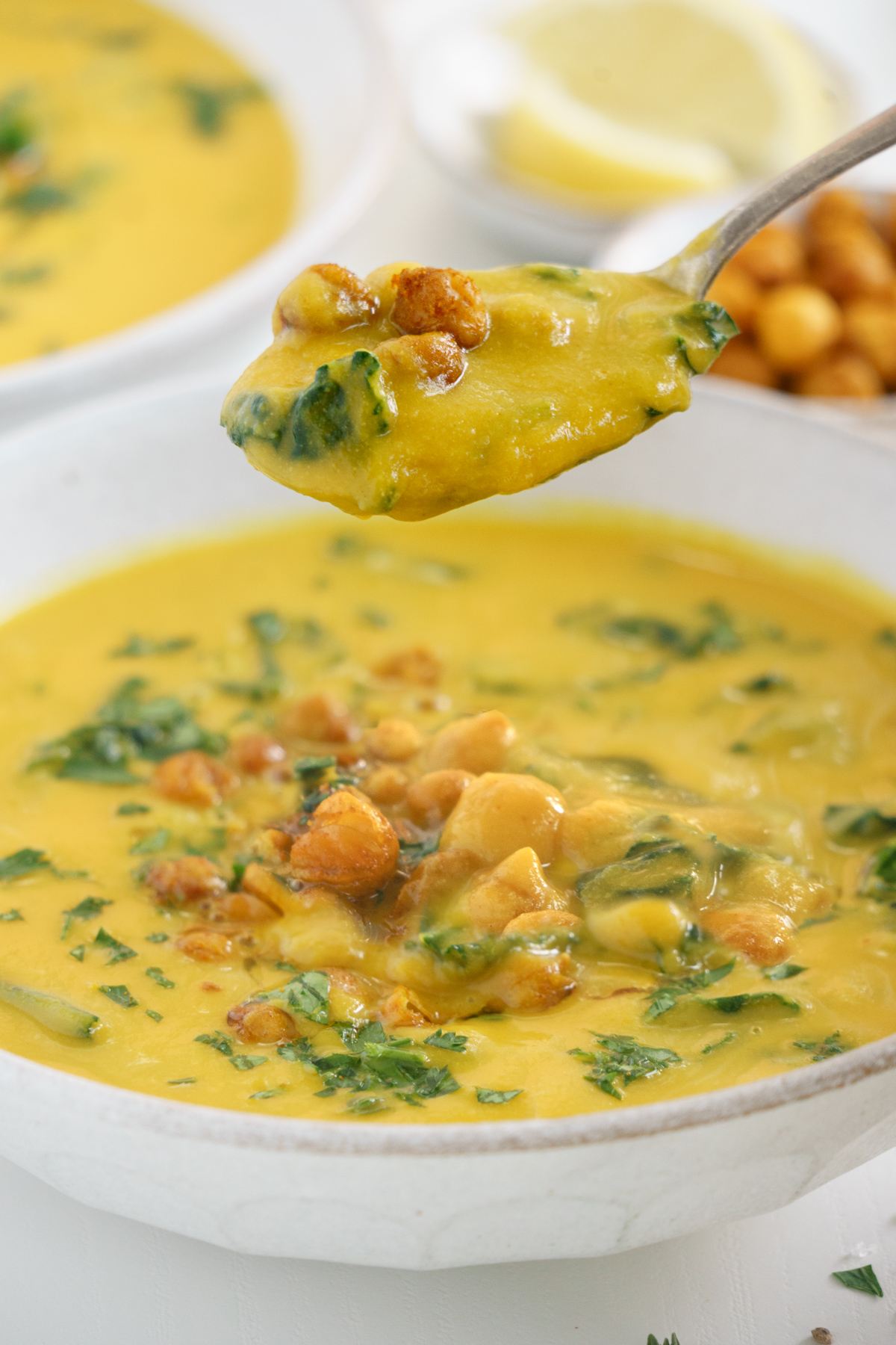 A spoon dipping a spoonful of turmeric chickpea soup up to take a bite.