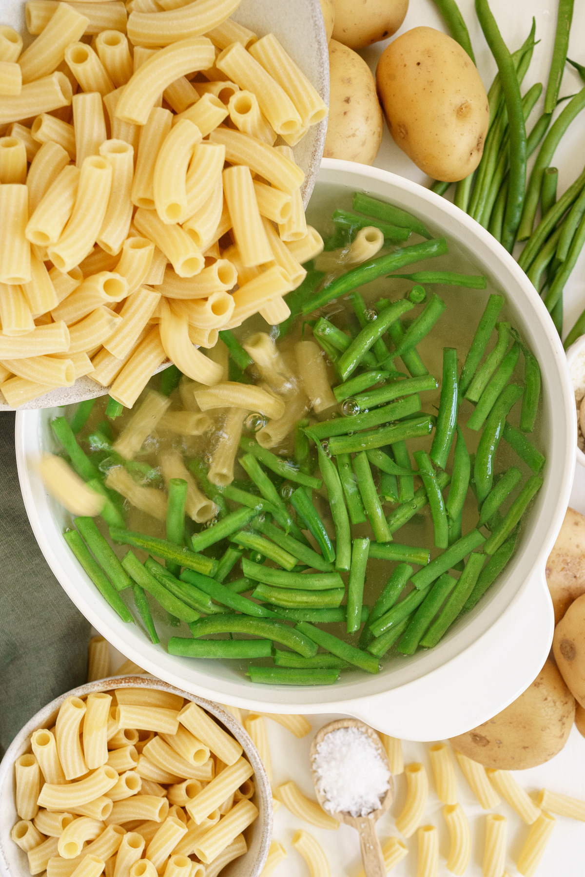 Top view of adding raw pasta into a boiling pot with vegetables