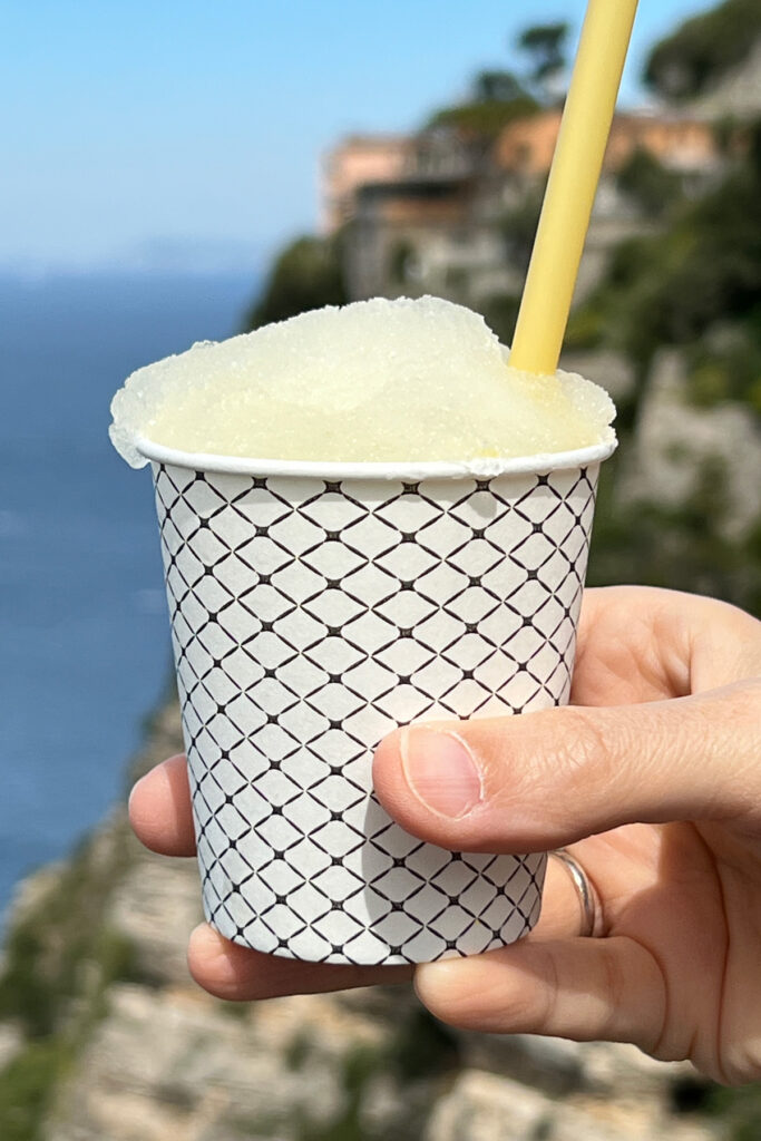 Hand holding a paper glass with granita al limone