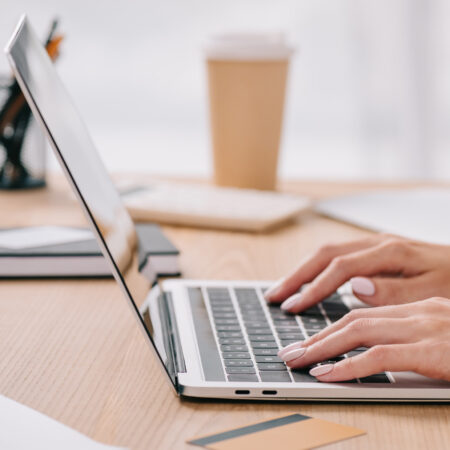 Side view of woman using a laptop at table working on a transcription job.