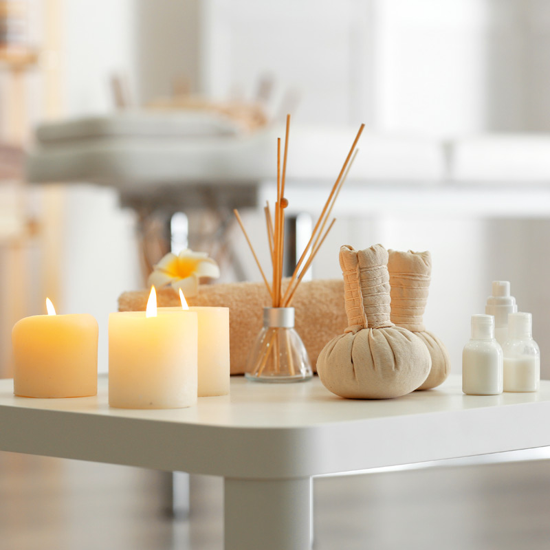Home accessories on a white table, including candles and fragrances 