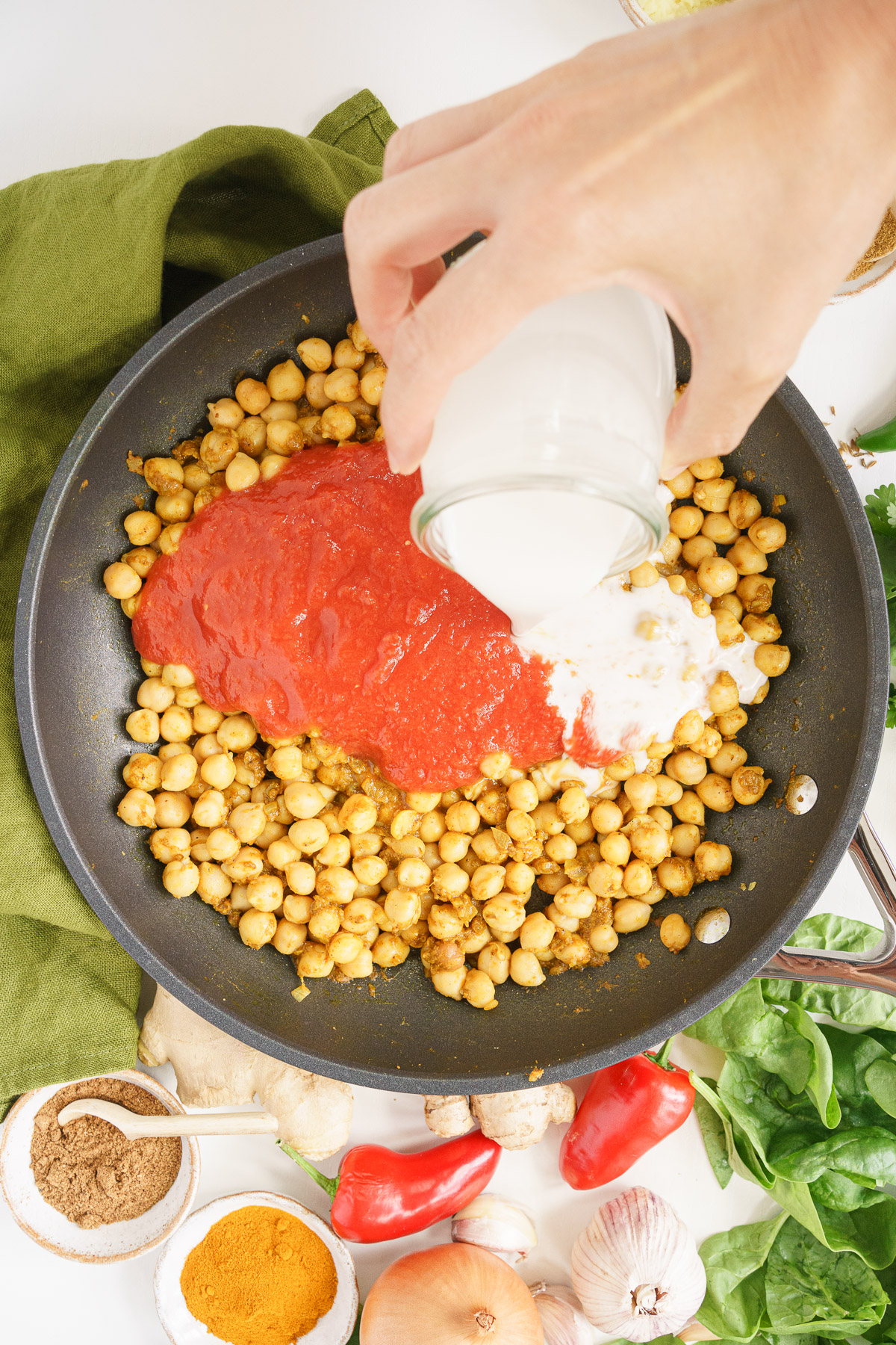 Adding the coconut milk and tomatoes to the skillet.