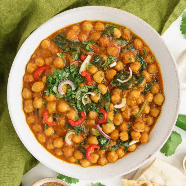 Bowl of vegan chickpea curry with cilantro and chilies on top.