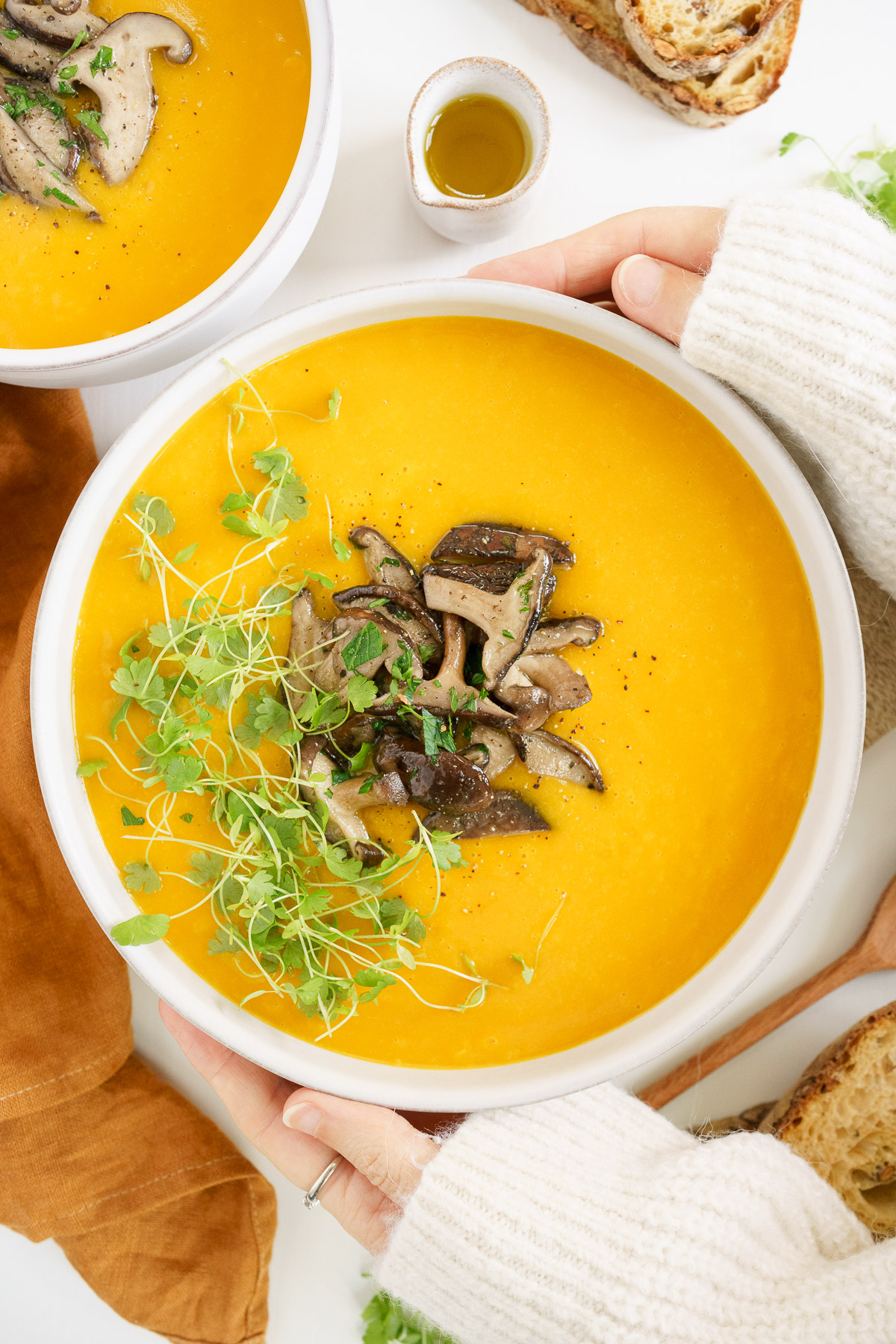 top view of hands holding a bowl full of pumpkin soup