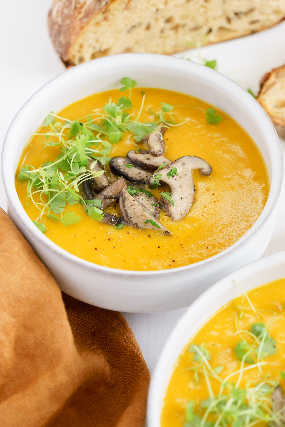 close up view of the creamy pumpkin soup in a bowl top with mushroom and parsley