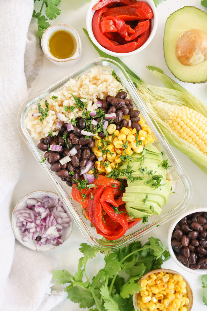 Mexican rice bowl with black beans, corn and rice in a glass container to go.