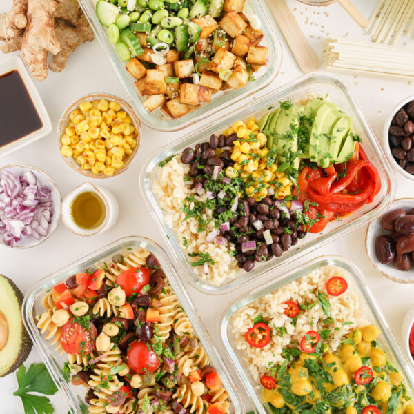 A colorful table filled with vegan meal prep bowls and lots of fresh ingredients.