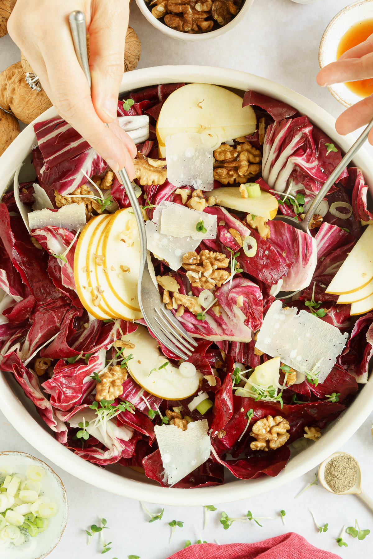 a hand tossing radicchio salad in a bowl with a fork