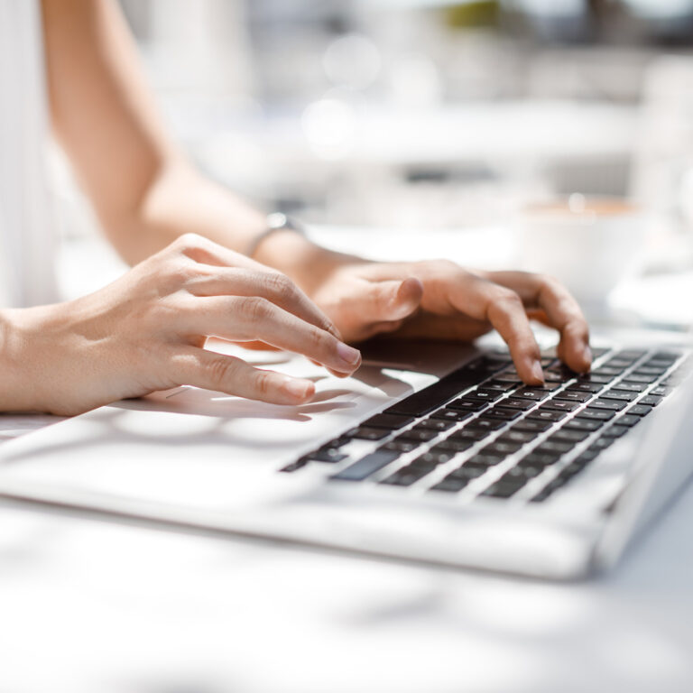 Woman's hands typing on a laptop