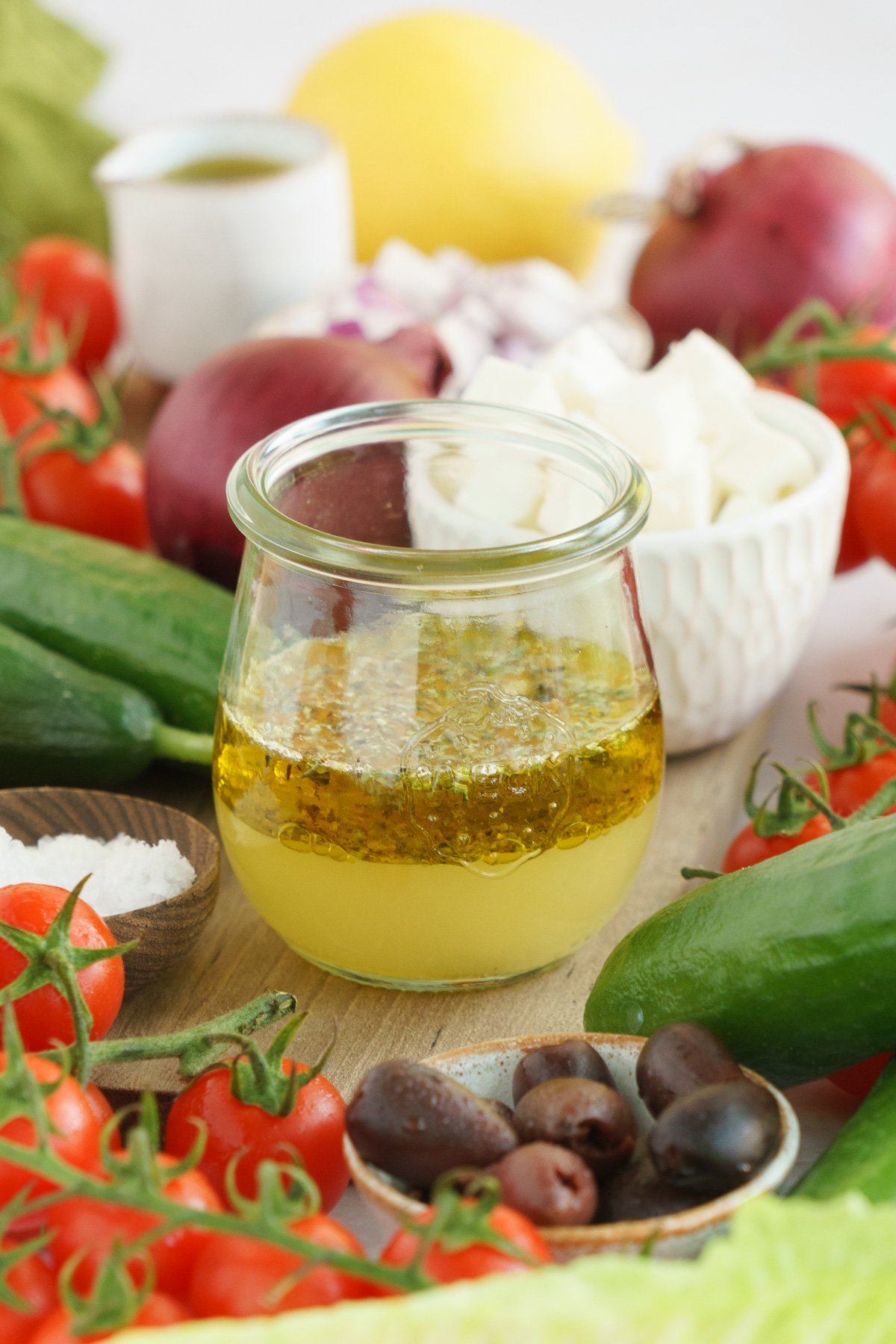 A mason jar filled with dressing ingredients including lemon juice, olive oil, oregano, salt, and pepper.