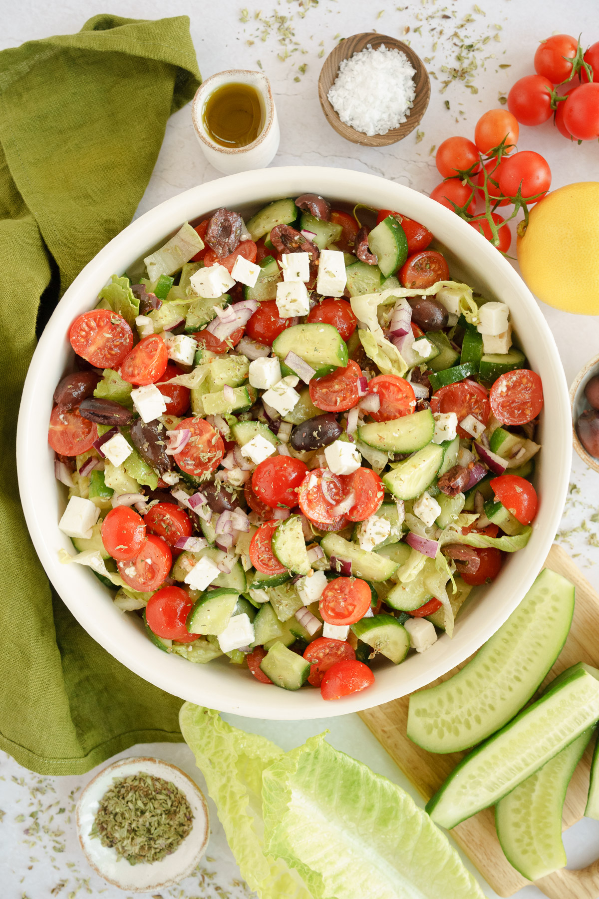 An overhead view of a big bowl of Greek salad with lettuce, tomatoes, cucumbers, red onions, feta cheese, and Kalamata olives