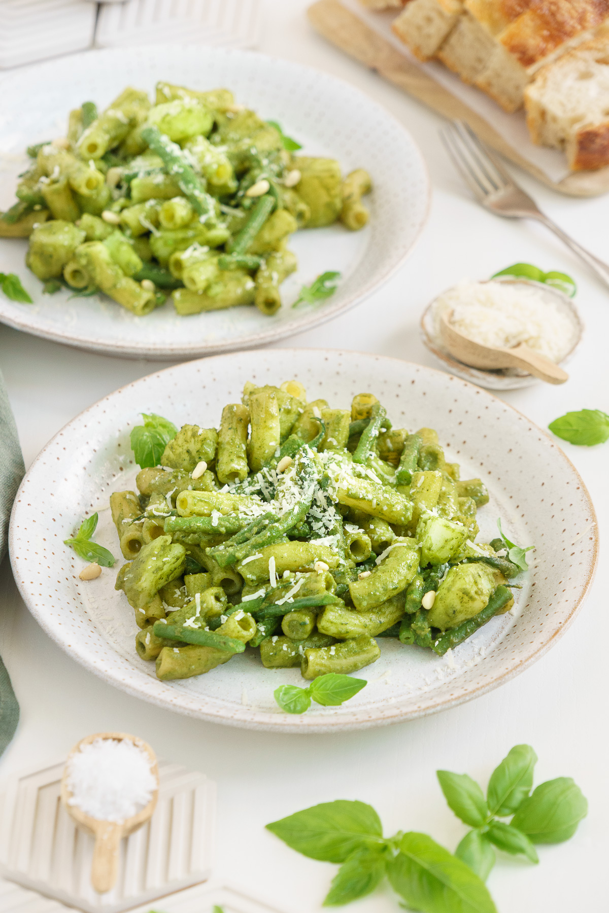 Angled view of two plates of basil pesto pasta
