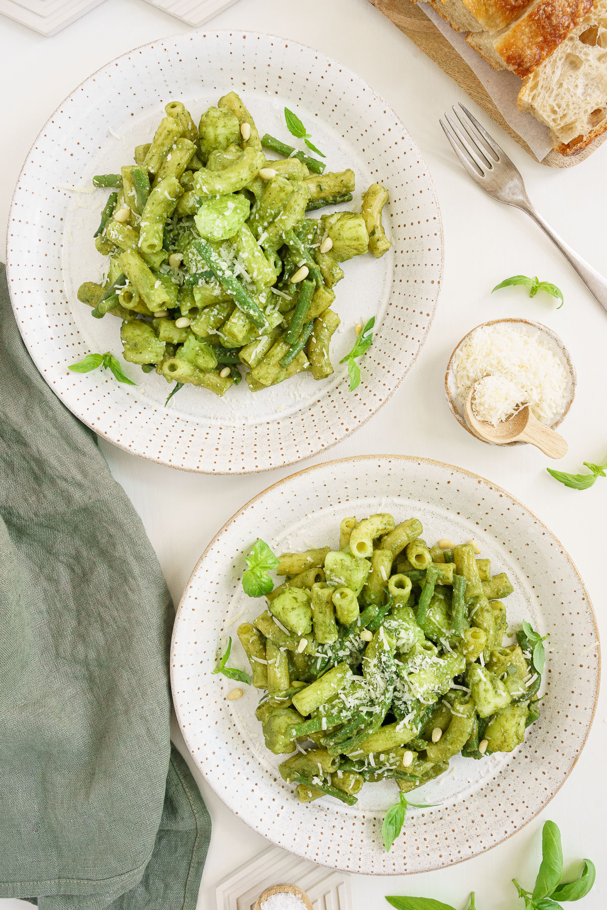 Top view of two plates of basil pesto pasta