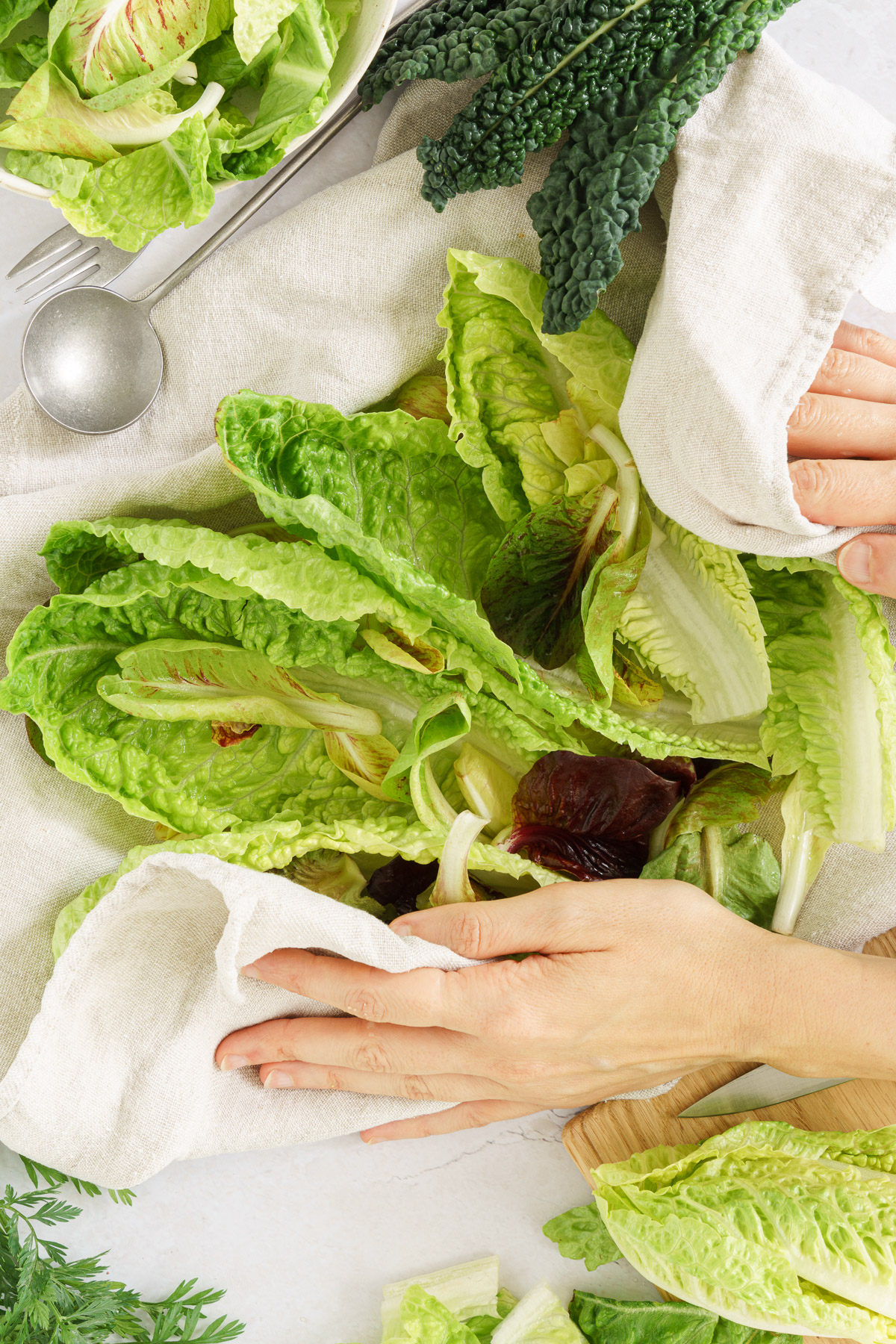 Hands drying salad leaves in a kitchen towel