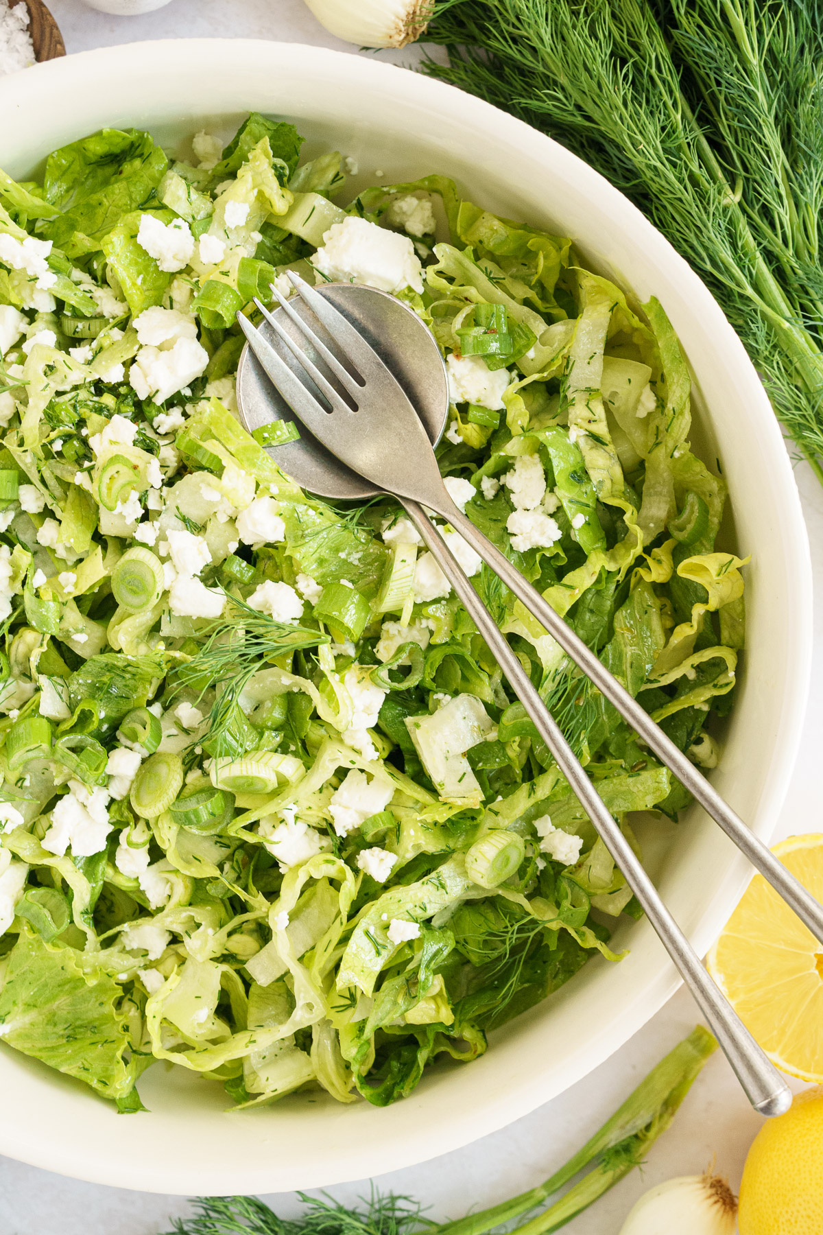 close up image of a bowl full of maroulosalata salad ingredients with spoon and fork