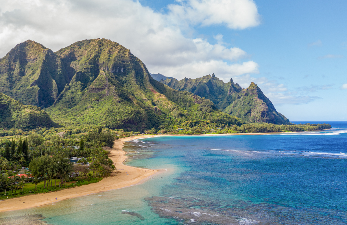 Aerial shot off the coast over Tunnels beach on Hawaiian island of Kauai with Na Pali mountains behind