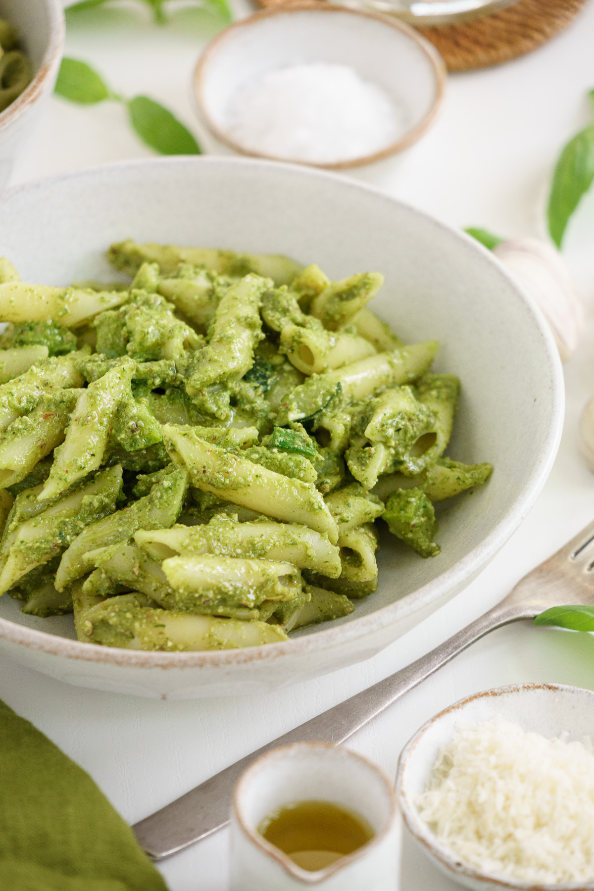A white bowl with zucchini pesto pasta on a table.