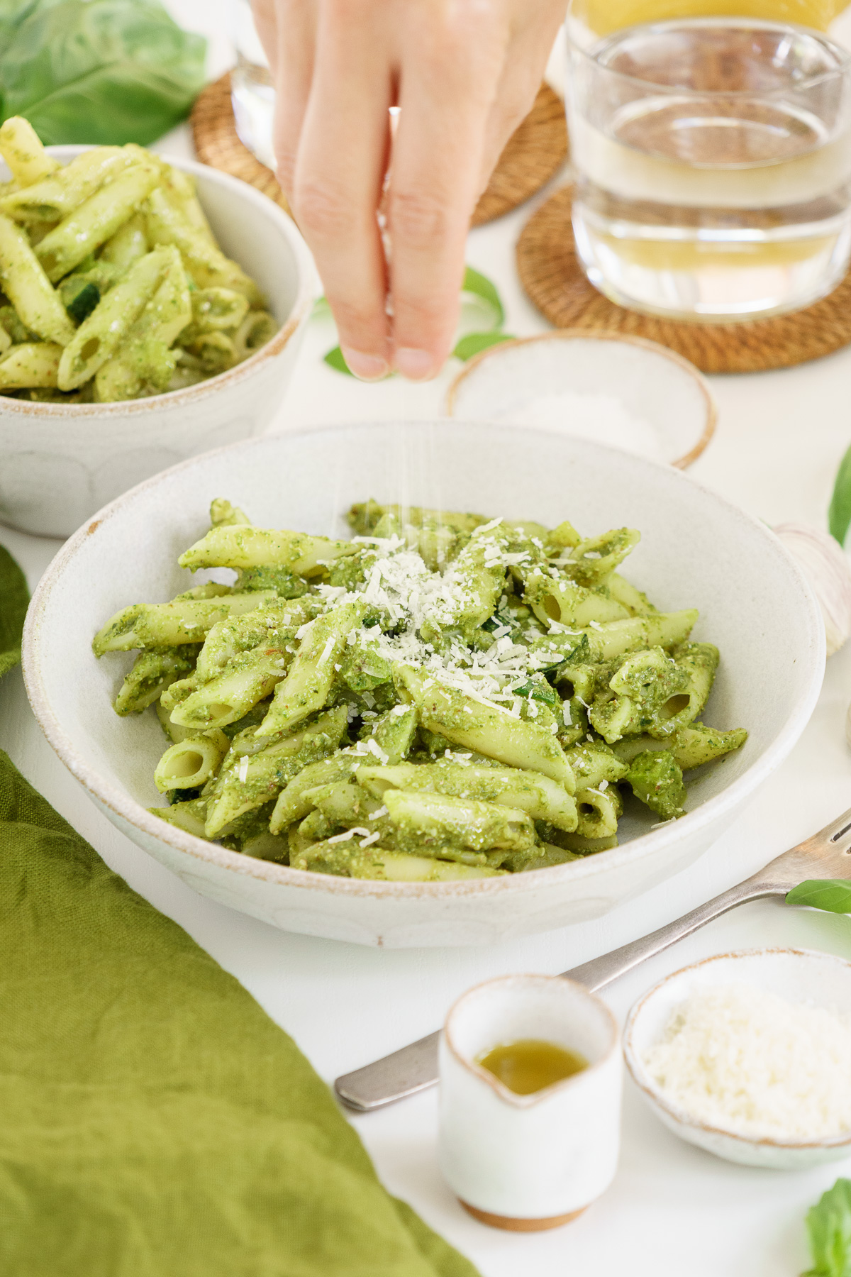 Hand adding parmesan on top of a bowl filled with pasta
