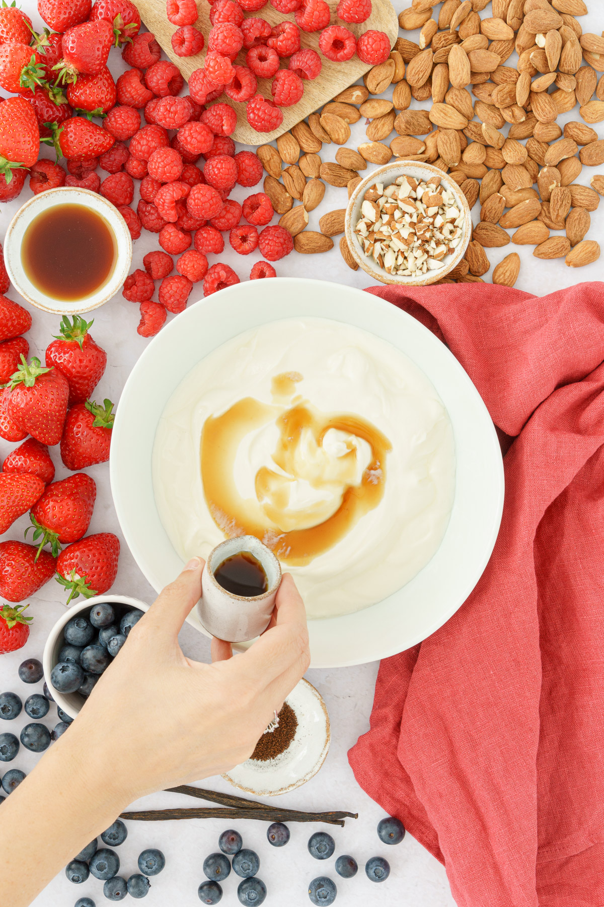 a hand pouring maple syrup into the yogurt