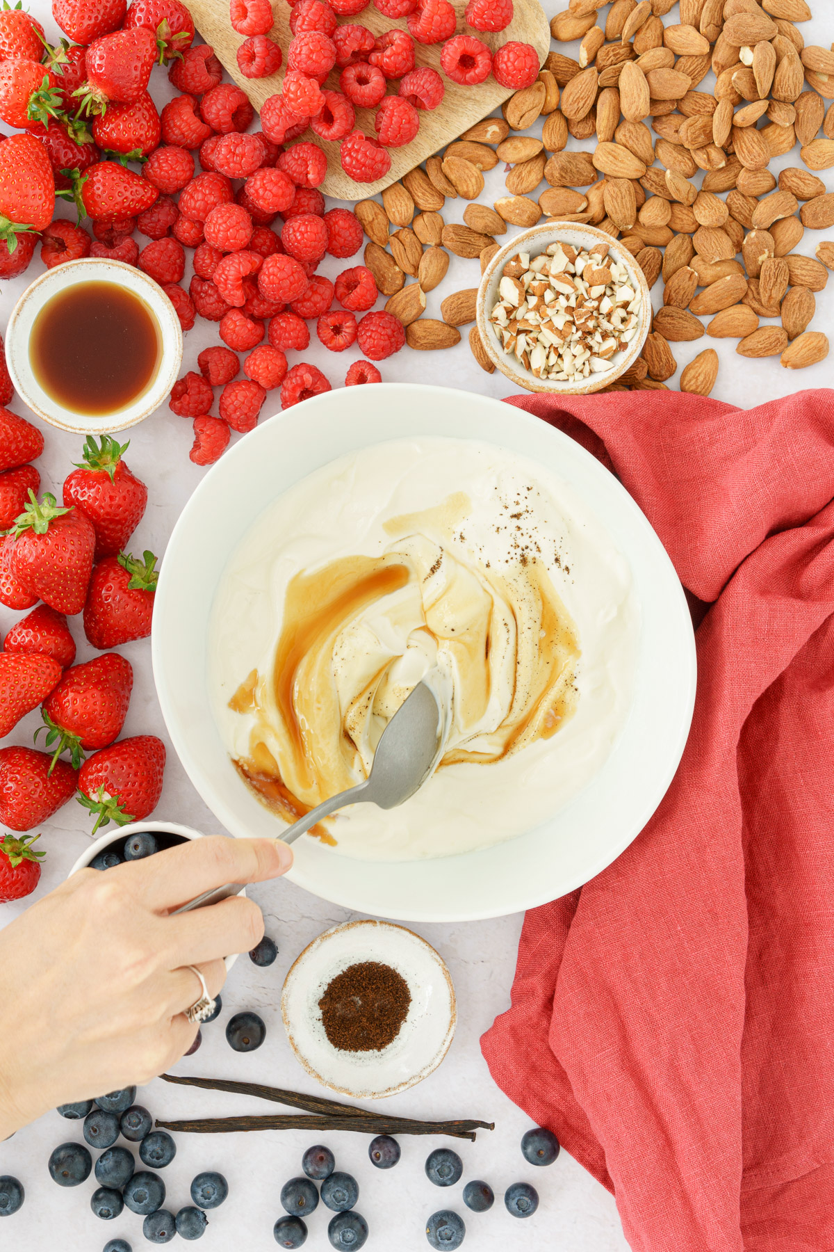 a hand mixing the yogurt with maple syrup using a spoon