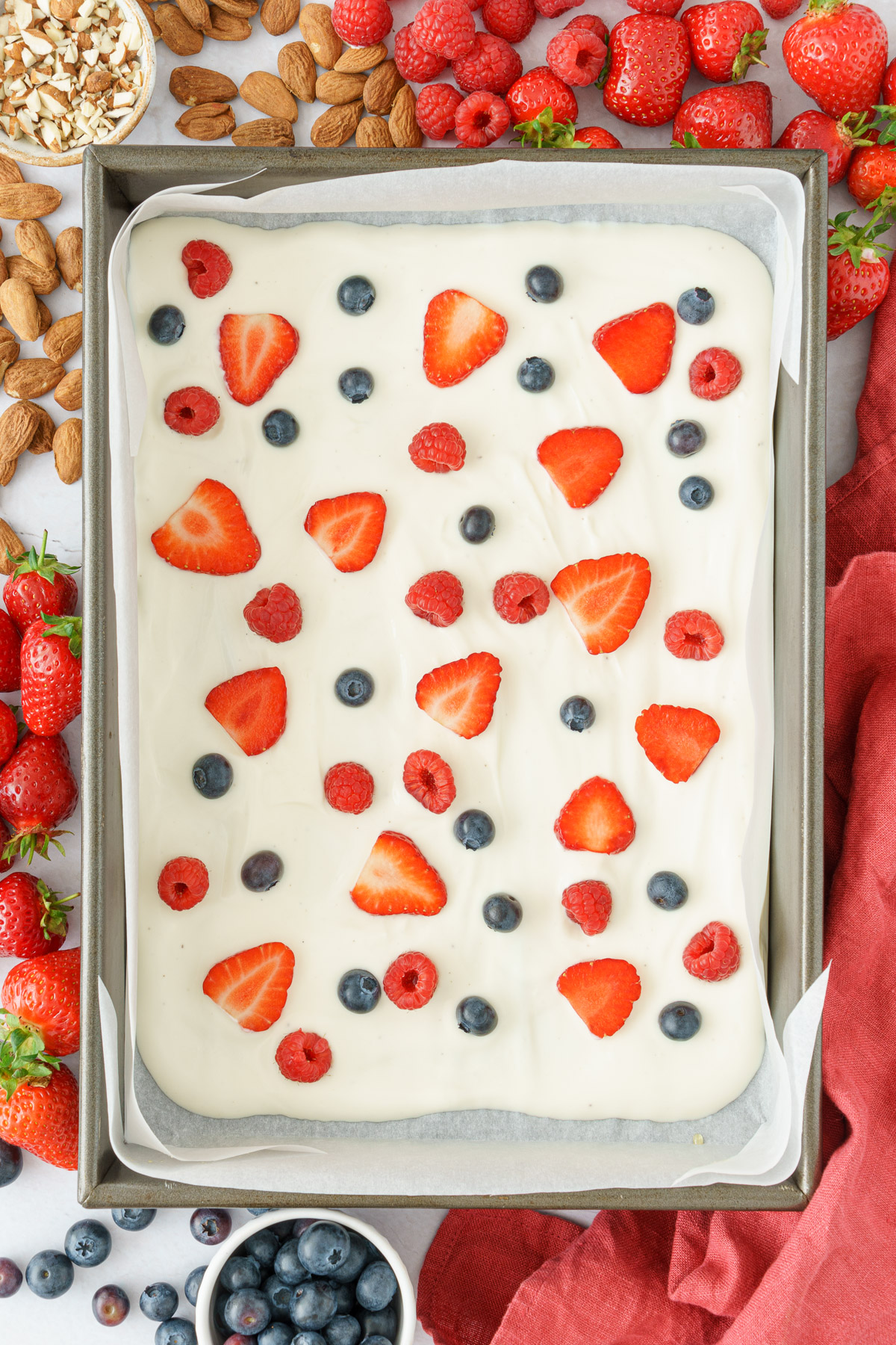 top view image of the baking sheet with yogurt, strawberries, blueberries, and raspberries