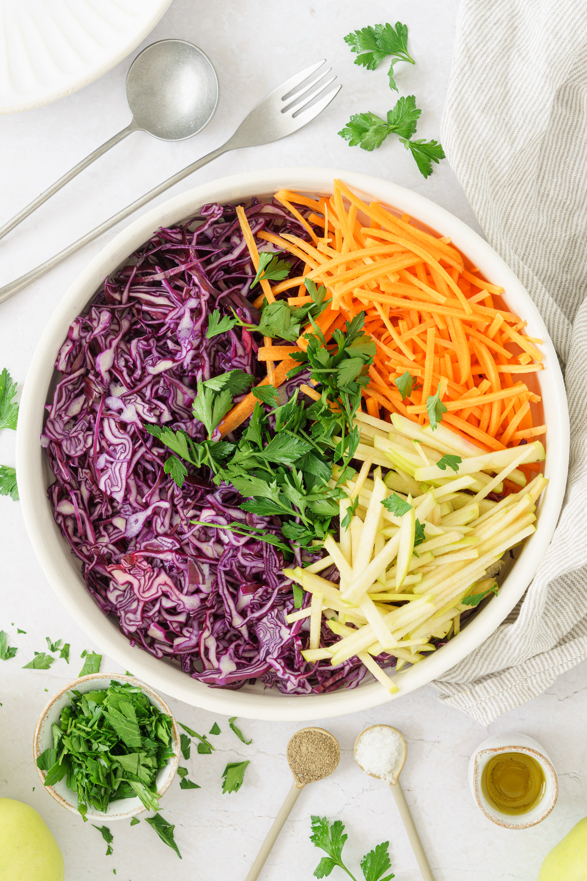 closed up image of bowl with combined thinly sliced red cabbage, apples, and carrots. 