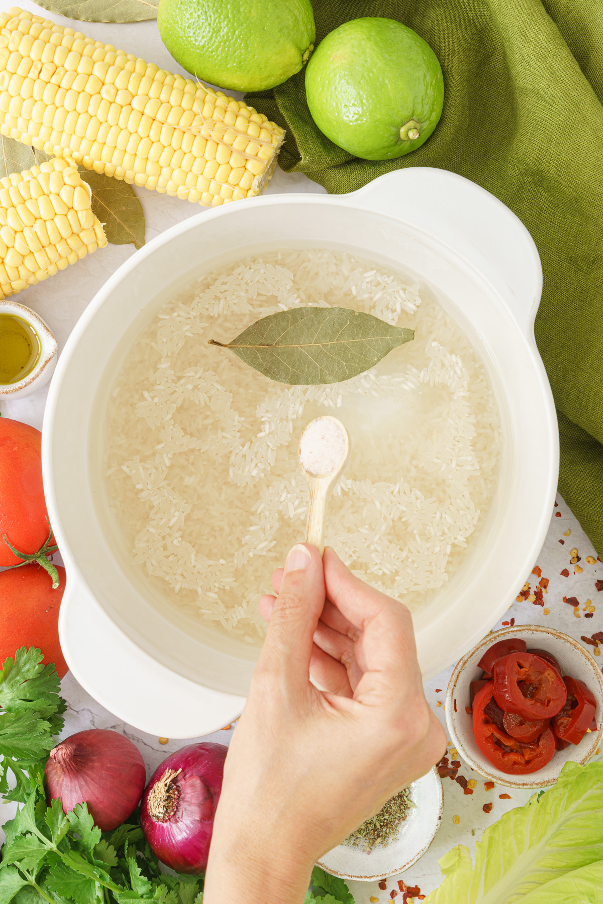 top view image of a pan with rice, water, and bay leaf