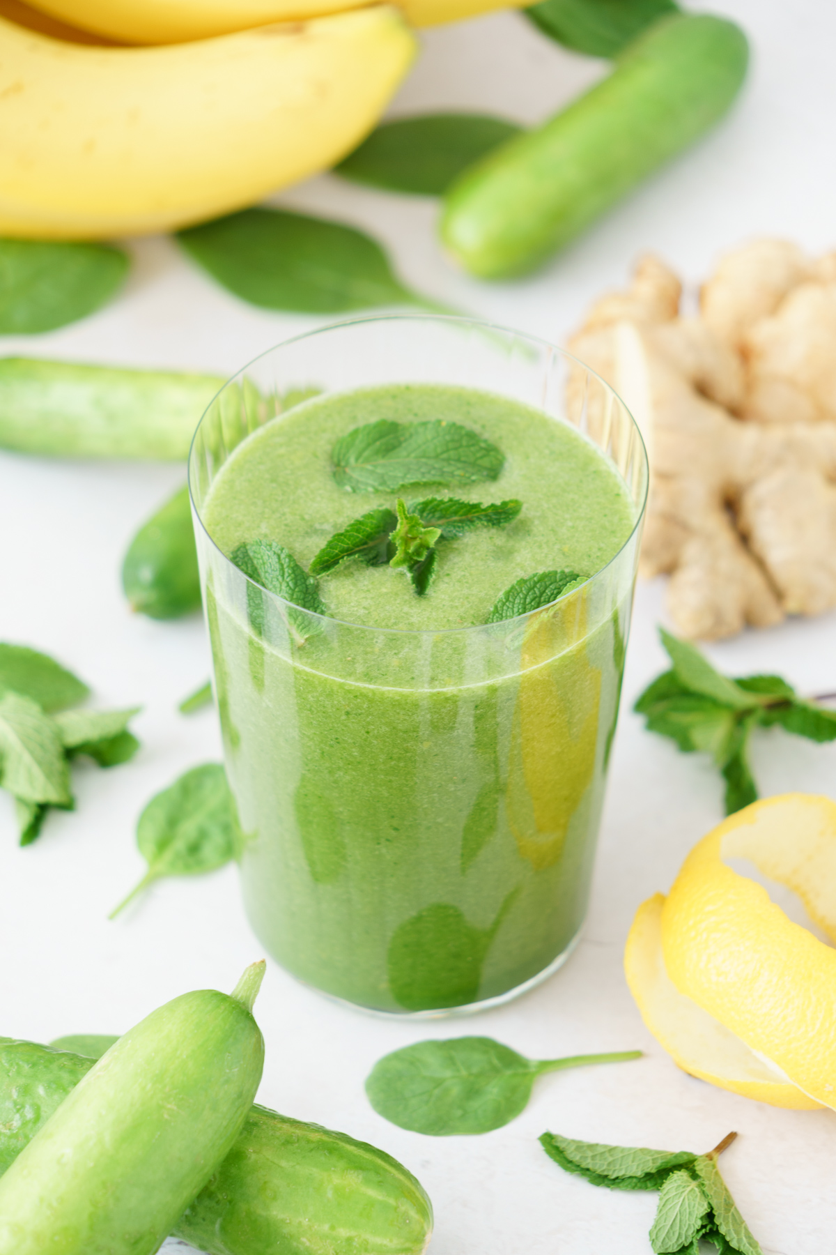 A glass full of creamy green detox smoothie top with mint leaves.