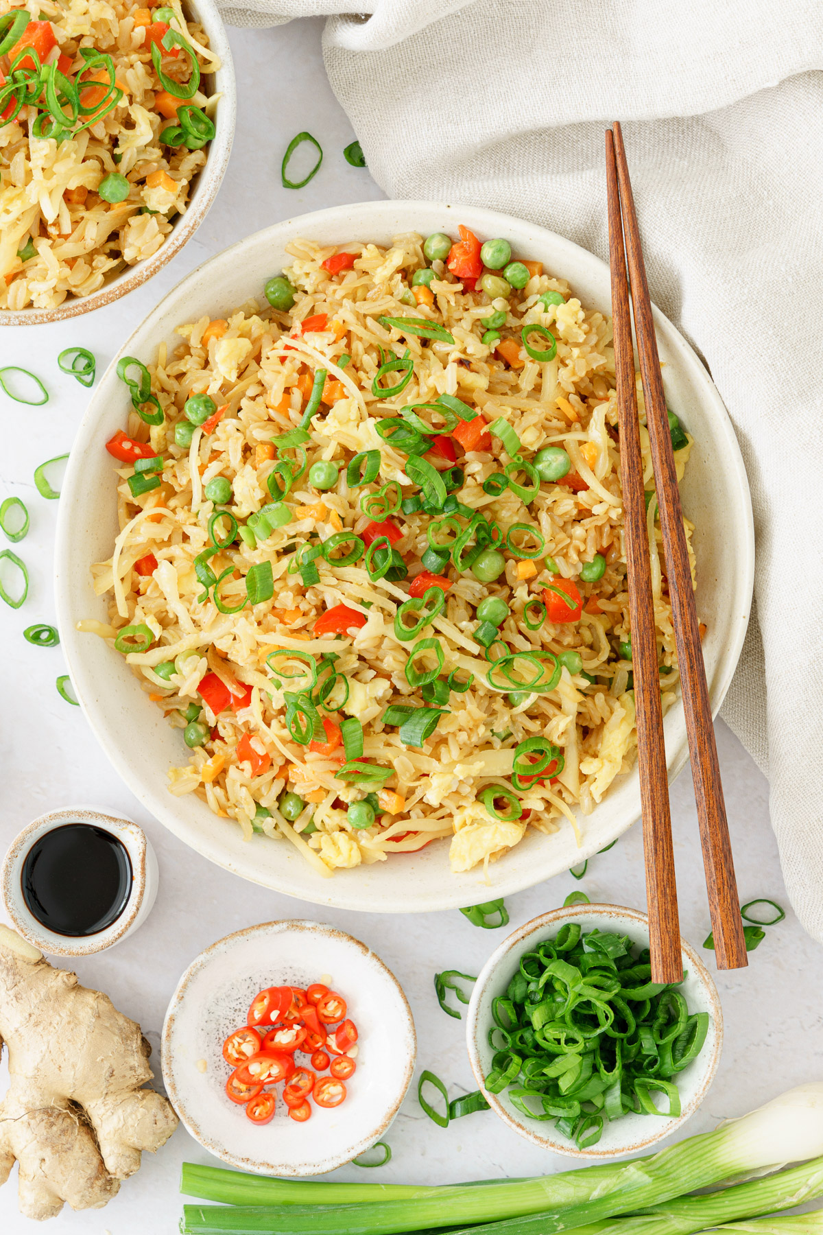 top image of a plate full of fried rice with spring onions toppings with a chopsticks