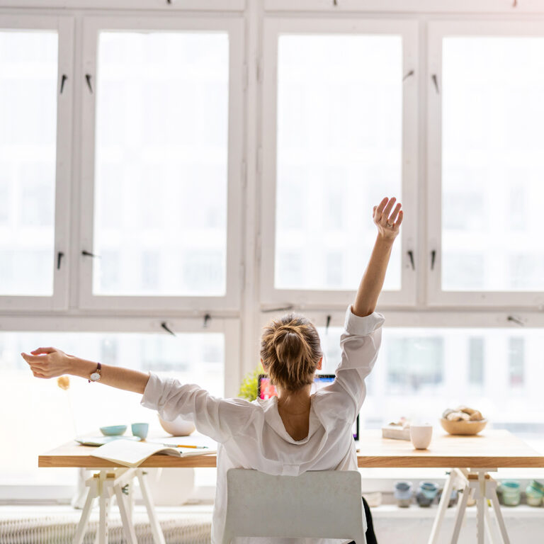 Woman stretching her arms while working in front of a laptop