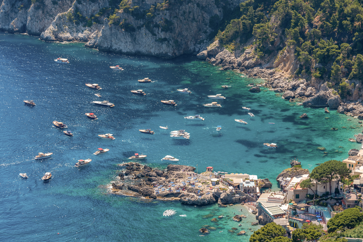 Motor boats floating around marina piccola in Capri island, Italy.